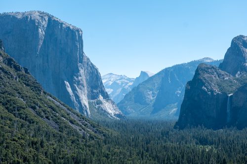 Free Scenic summer view of Yosemite Valley's iconic granite cliffs and forested valley. Stock Photo
