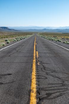 Long straight road leading through the desert landscape of Nevada, USA.