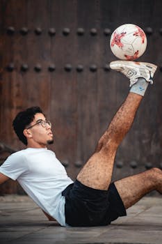 A man balances a soccer ball on one foot outdoors. Showcasing sportsmanship and talent.