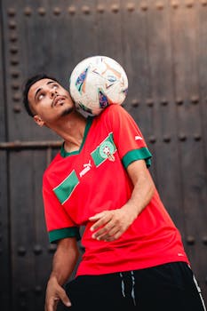 Male soccer player showcasing skills by balancing a ball on his head.