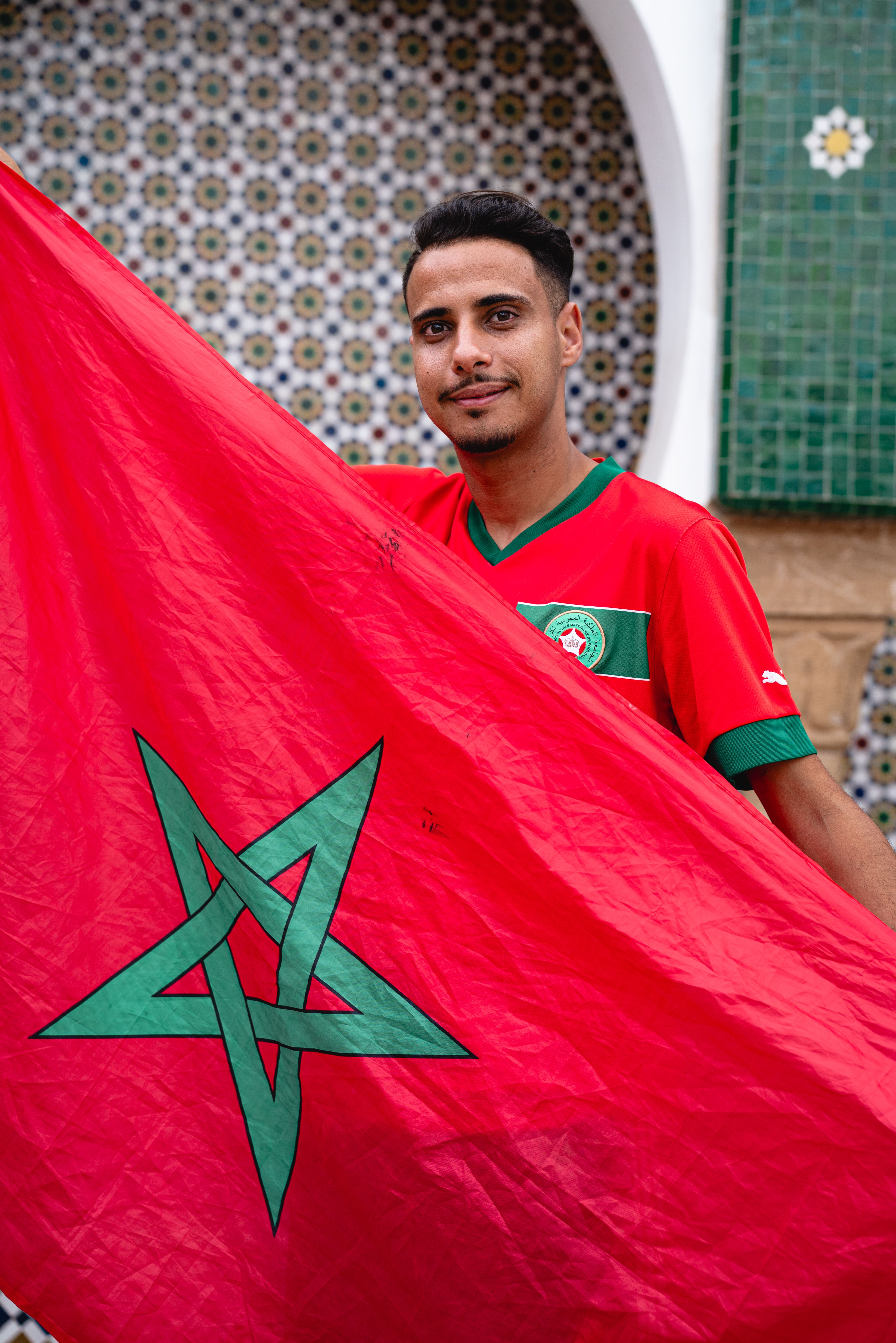 Young Moroccan man holding the national flag, displaying pride and patriotism.