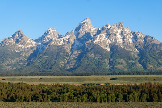 A stunning view of the Grand Teton Mountains in Wyoming during a sunny day, showcasing their rugged peaks.