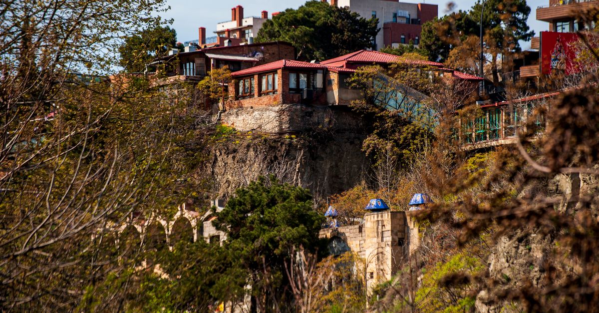 Traditional hillside homes in Tbilisi, Georgia, surrounded by lush spring foliage.