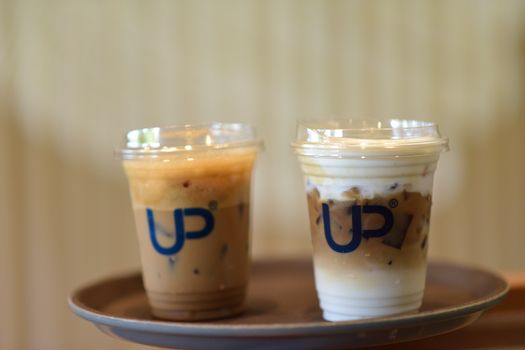 Close-up of two iced coffee cups on a tray in a cafe, featuring milk and espresso layers.