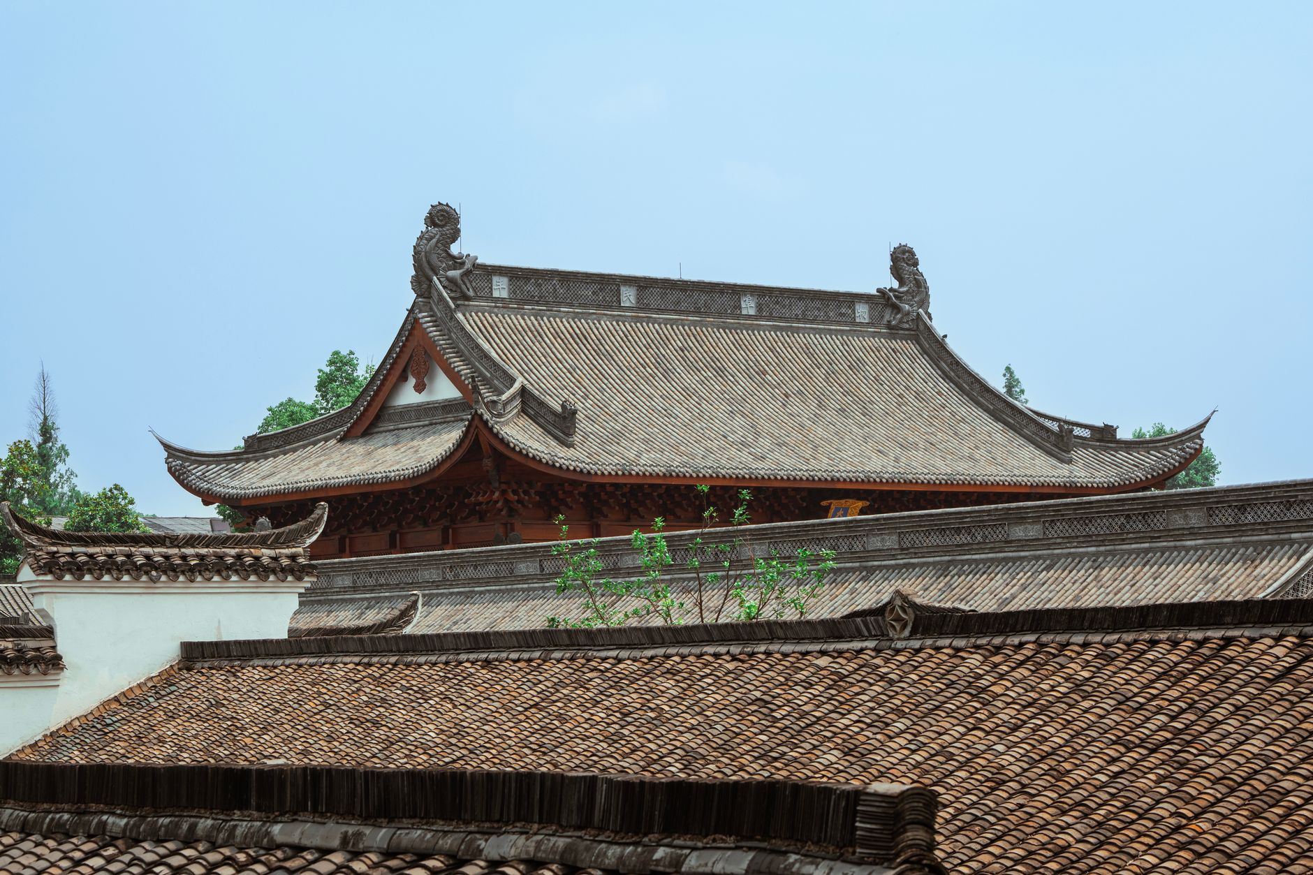 Intricate traditional Asian temple roof captured against a clear sky, showcasing detailed craftsmanship.