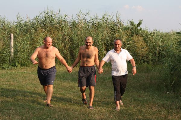 Three men walking and smiling together outdoors in nature
