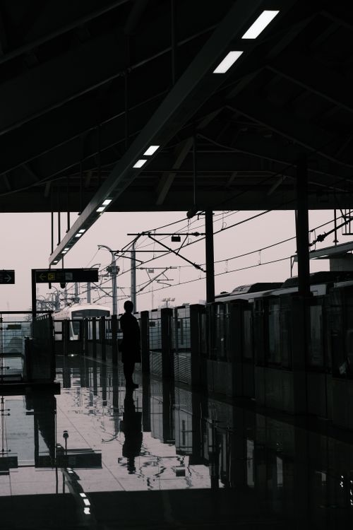 Free Moody silhouette of a lone traveler waiting at an urban train station. Stock Photo