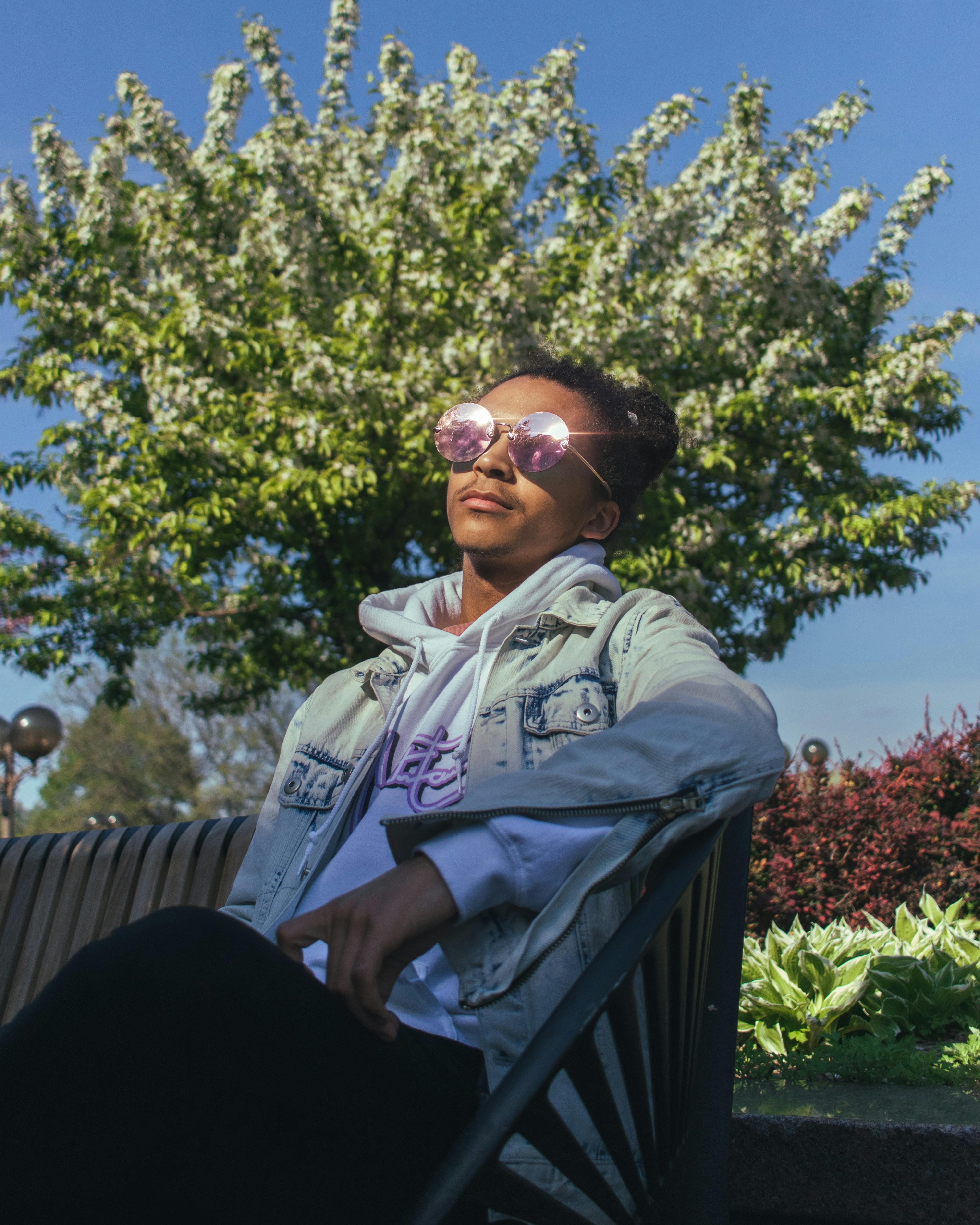 在阳光明媚的公园里，戴着太阳镜的时尚年轻人正放松身心