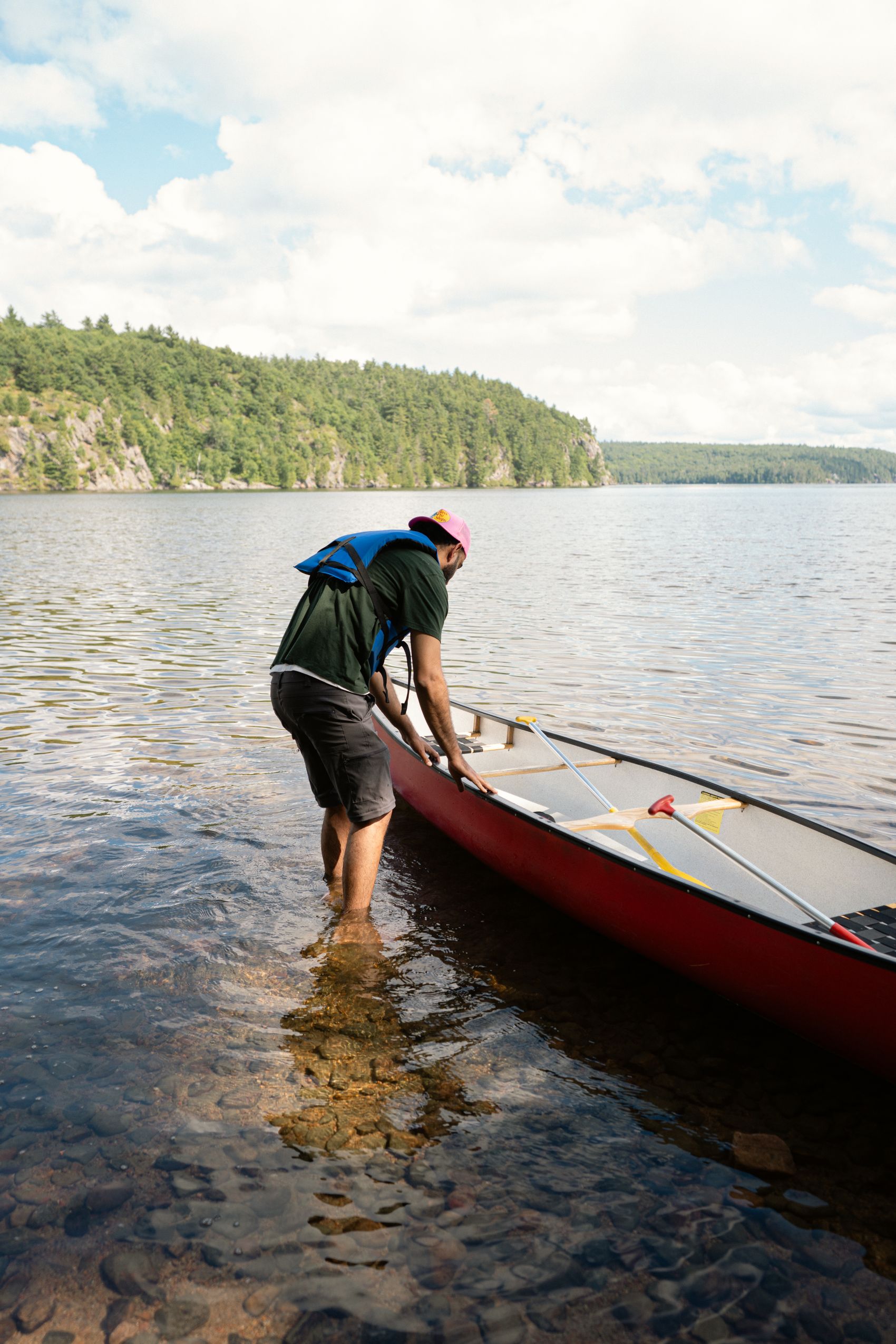 Kayaker wearing a life jacket preparing equipment beside a lake