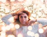 这是一幅温暖舒适的冬季肖像，一名女子躺在发光的节日灯光中，营造出节日气氛