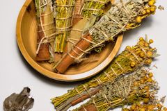 Dried herbal smudge sticks with crystals displayed on a white surface.
