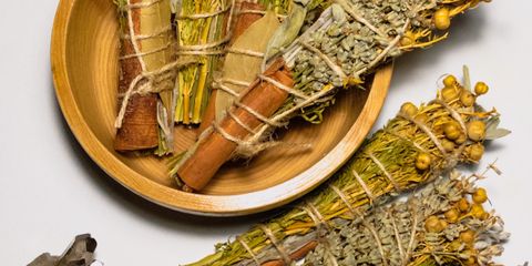 Dried herbal smudge sticks with crystals displayed on a white surface.