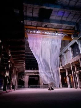 Large translucent drape illuminated in an abandoned industrial building.