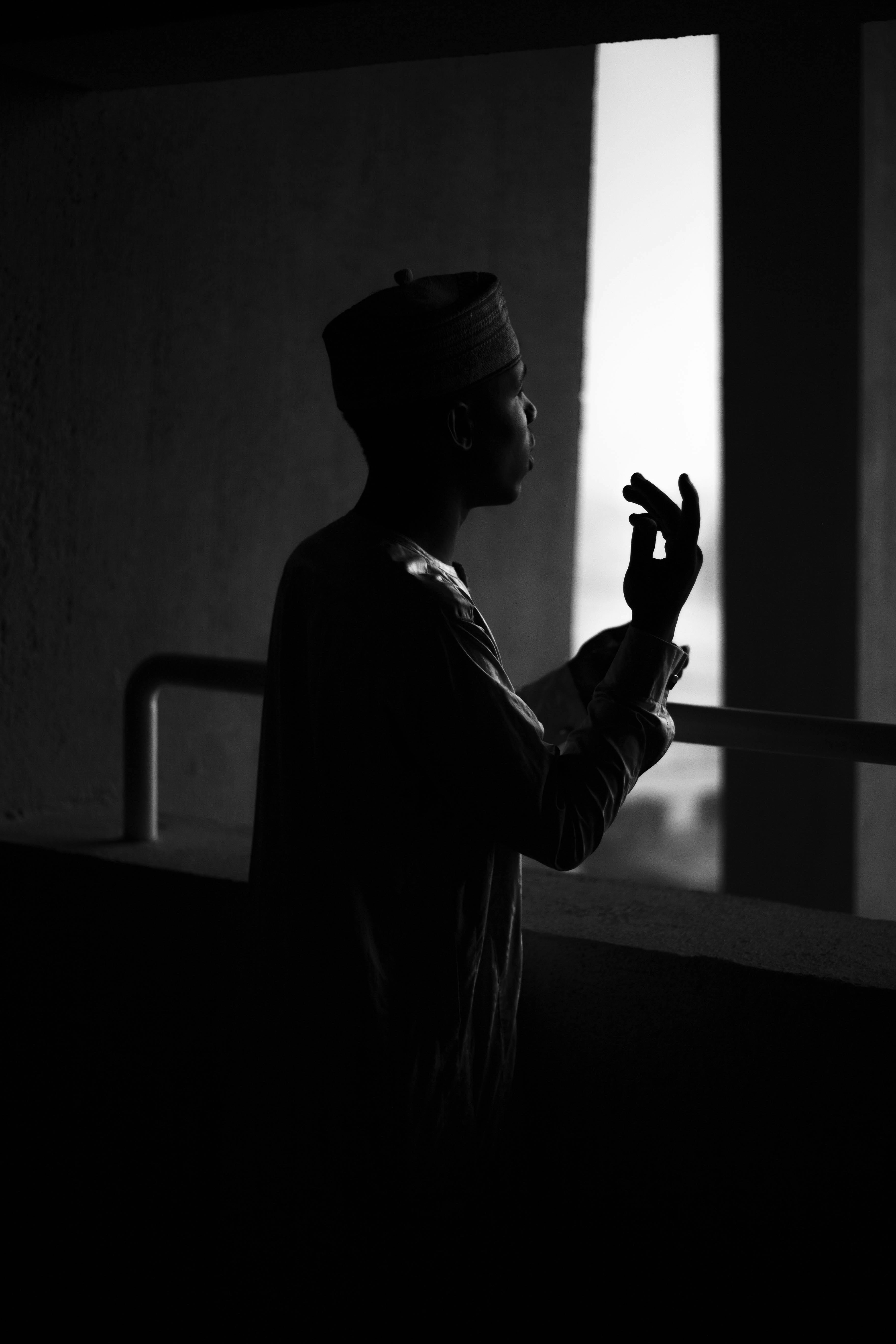 Gratis Silhuet af en mand i traditionelt tøj inde i en svagt oplyst bygning. Lagerfoto