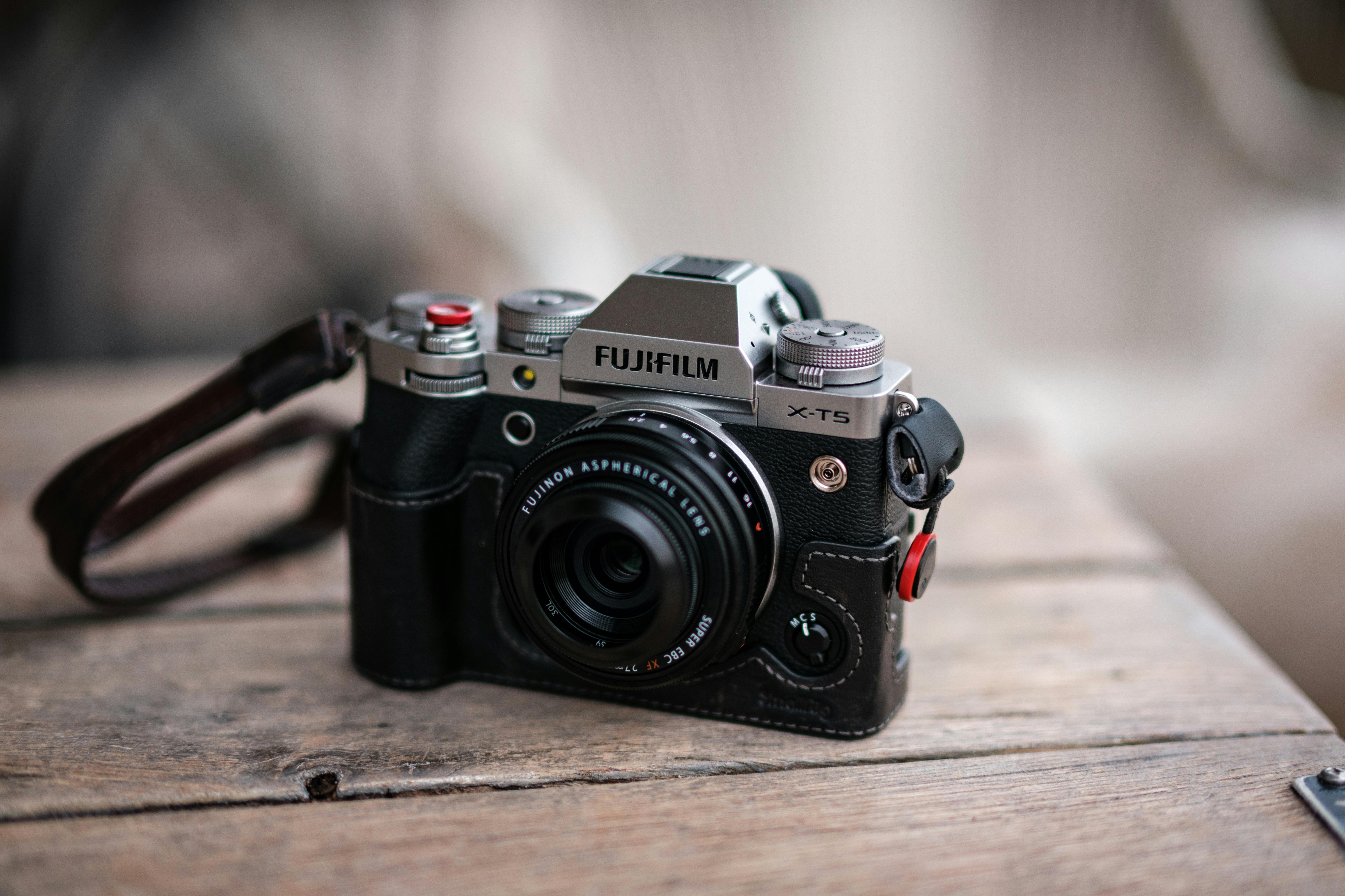 Close-up of a Fujifilm X-T5 camera placed on a rustic wooden table, perfect for photography enthusiasts.