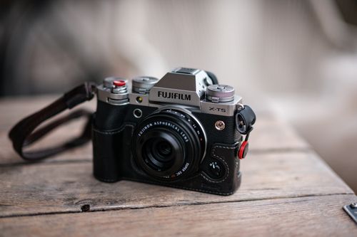 Free Close-up of a Fujifilm X-T5 camera placed on a rustic wooden table, perfect for photography enthusiasts. Stock Photo