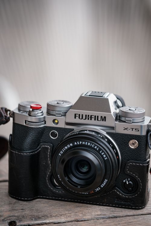 Free Close-up of a Fujifilm X-T5 mirrorless camera on a wooden surface indoors. Stock Photo