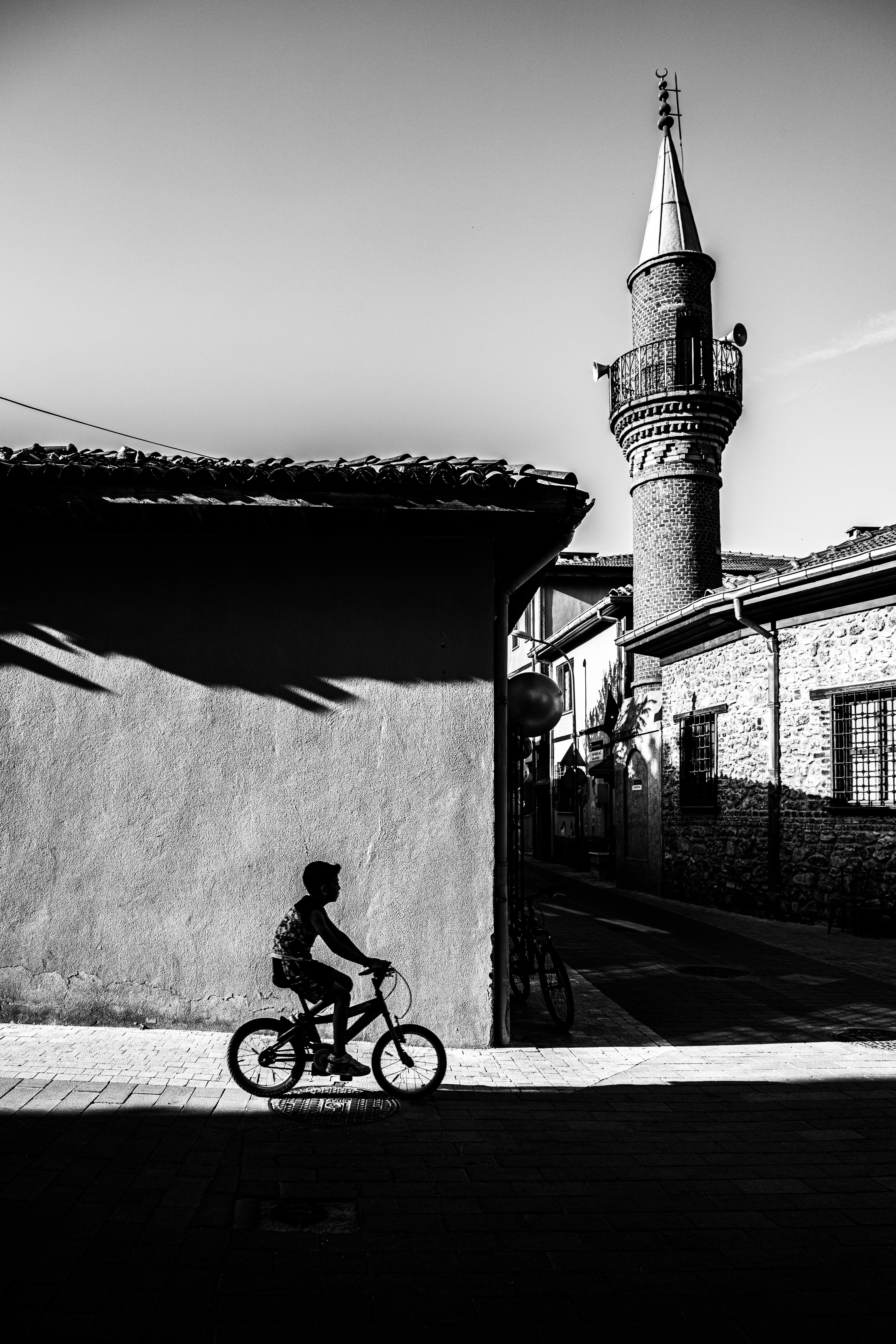 Black and white silhouette of a cyclist near a historic mosque in Bursa, Türkiye.