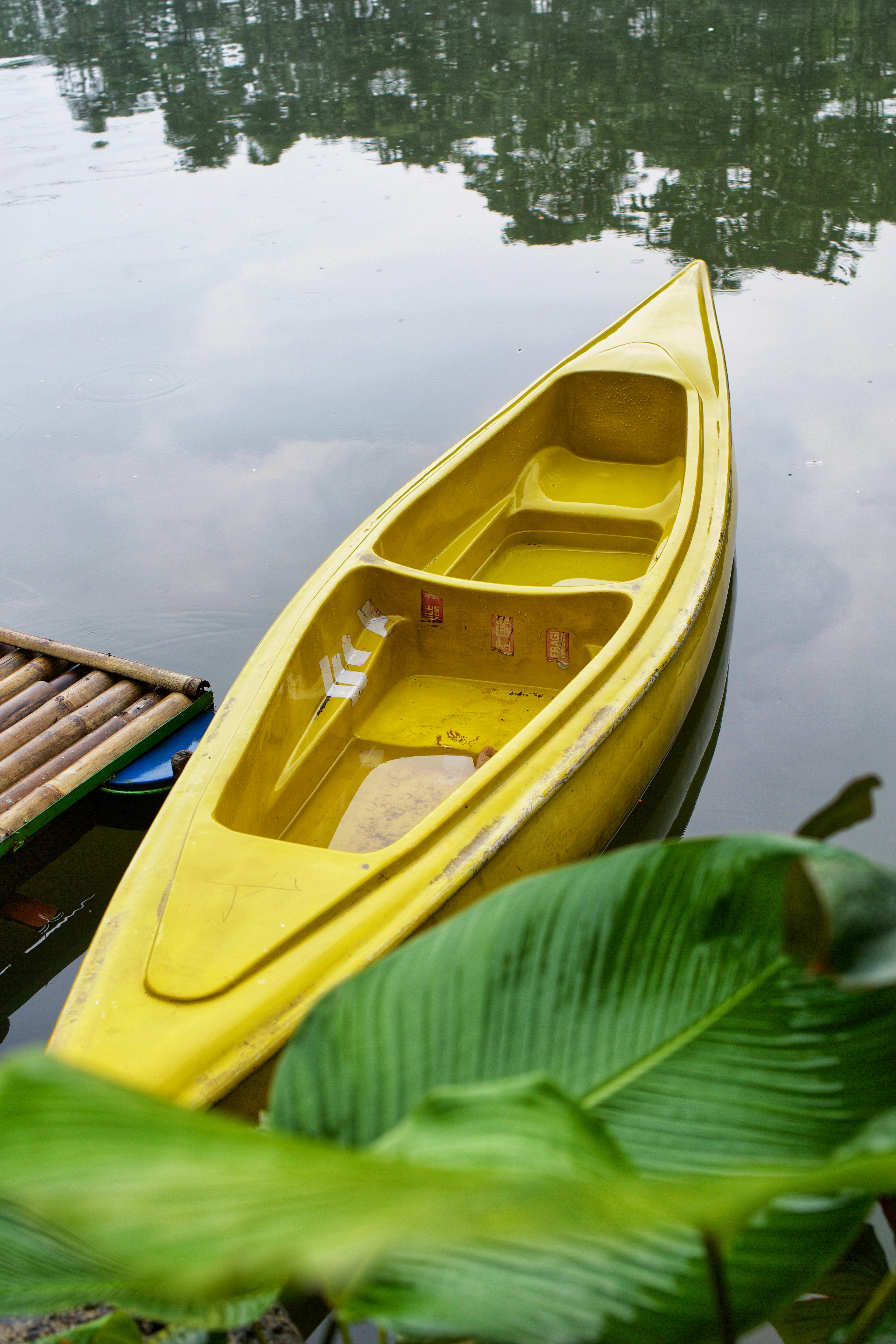Serene image of a yellow canoe docked on a calm lake surrounded by nature.