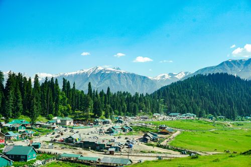 Free Picturesque mountain village surrounded by lush forests and majestic peaks on a sunny day. Stock Photo