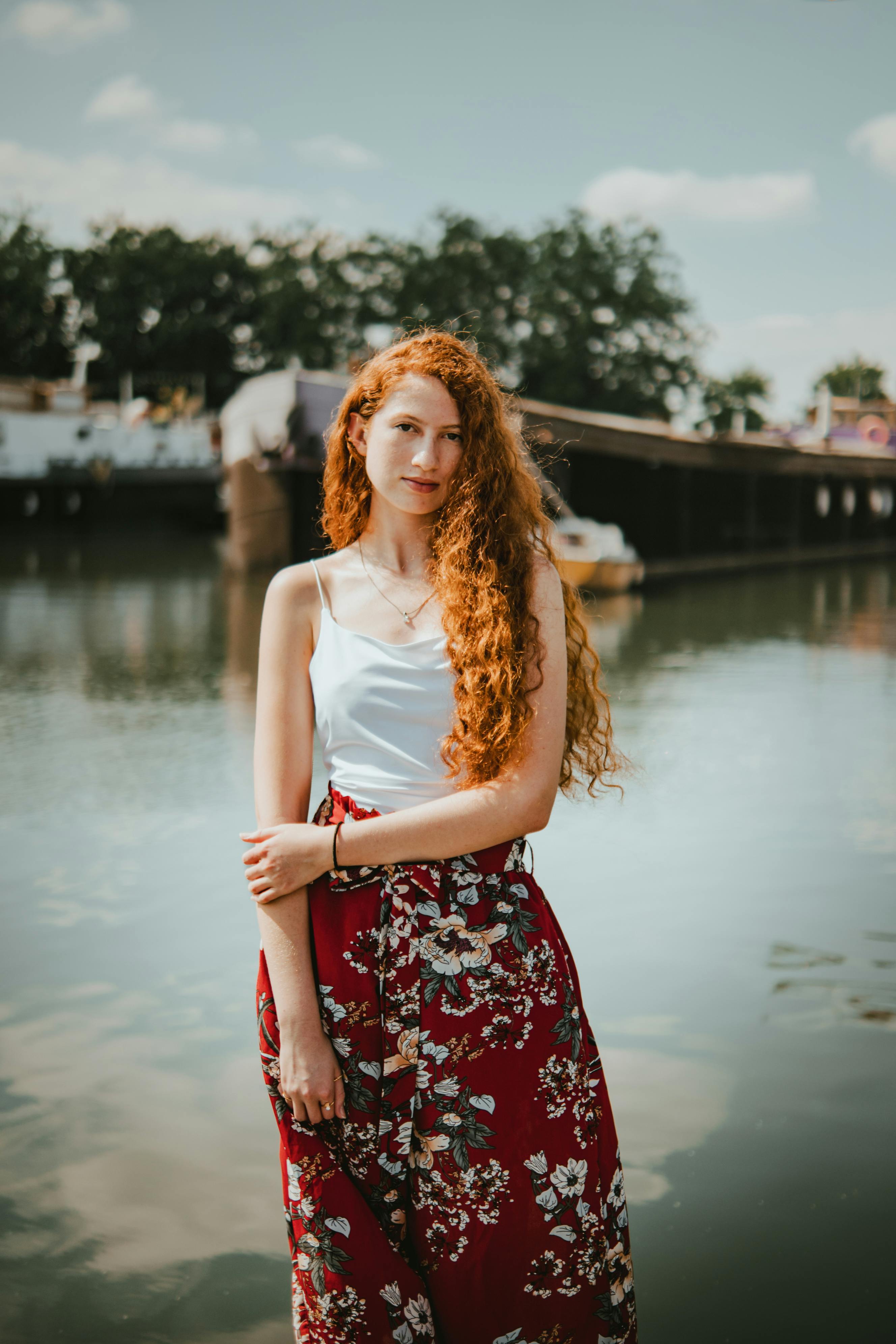 Beautiful woman with long red hair next to a river in Lille, France, on a sunny day.
