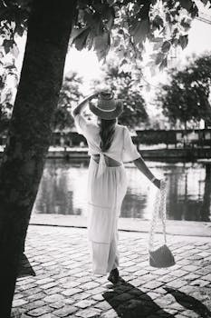 Elegant woman in a dress and hat walking by a canal in Lille, France.