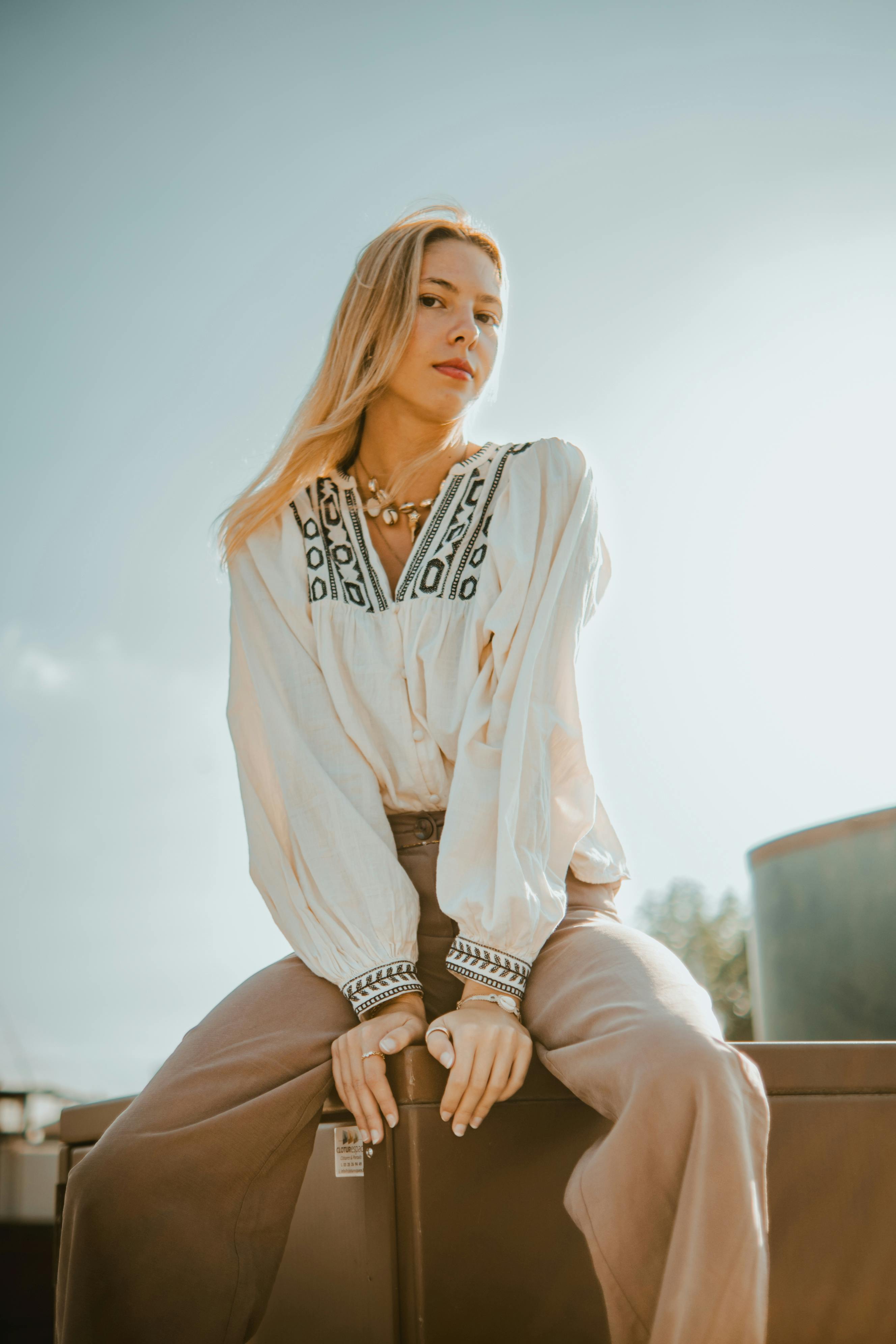 Elegant woman in bohemian attire posing outdoors under a clear sky.