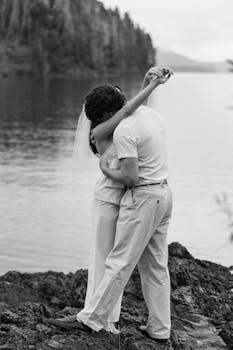 A black and white photo of a couple embracing by the lake in Bariloche, Argentina.