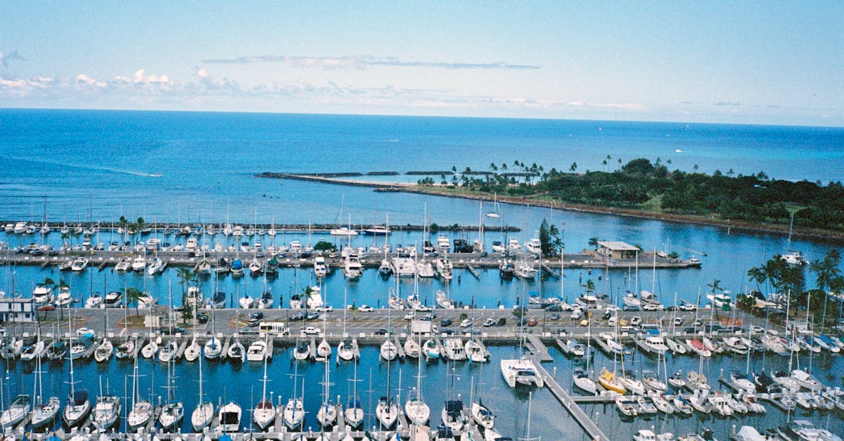 Photo by Ichear Xue Aerial view of boats docked in Honolulu Harbor, Hawaii, with vibrant ocean scenery.