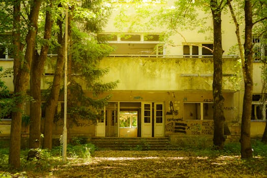Mysterious abandoned building covered in graffiti, surrounded by lush trees in Ohrid, North Macedonia.