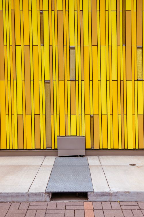Free Modern architectural yellow wall with a striped pattern, creating a bold visual impact. Stock Photo
