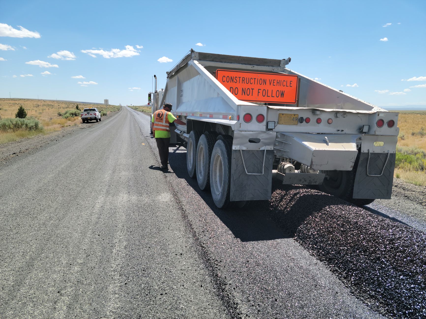 Construction vehicle working on a highway in rural Oregon, USA, under bright daylight.