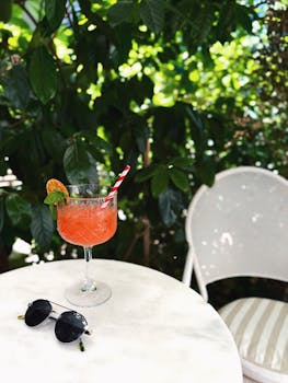A vibrant cocktail with sunglasses on a sunlit patio, perfect for summer leisure.