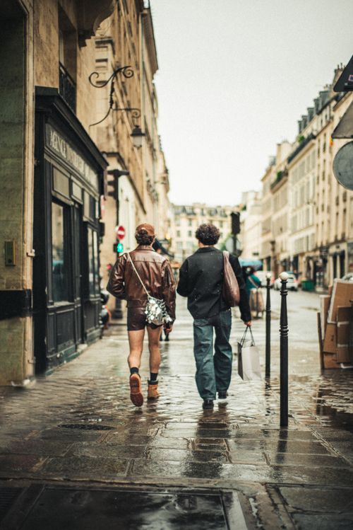 Free A couple walks down a rainy, historic street, showcasing European architecture. Stock Photo
