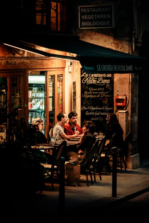 Free Group dining outdoors at a Parisian restaurant, warm ambiance, night. Stock Photo