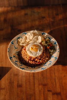 Plate of Indonesian fried rice with a sunny-side-up egg, crackers, and vegetables. - Fotografer Sidoarjo