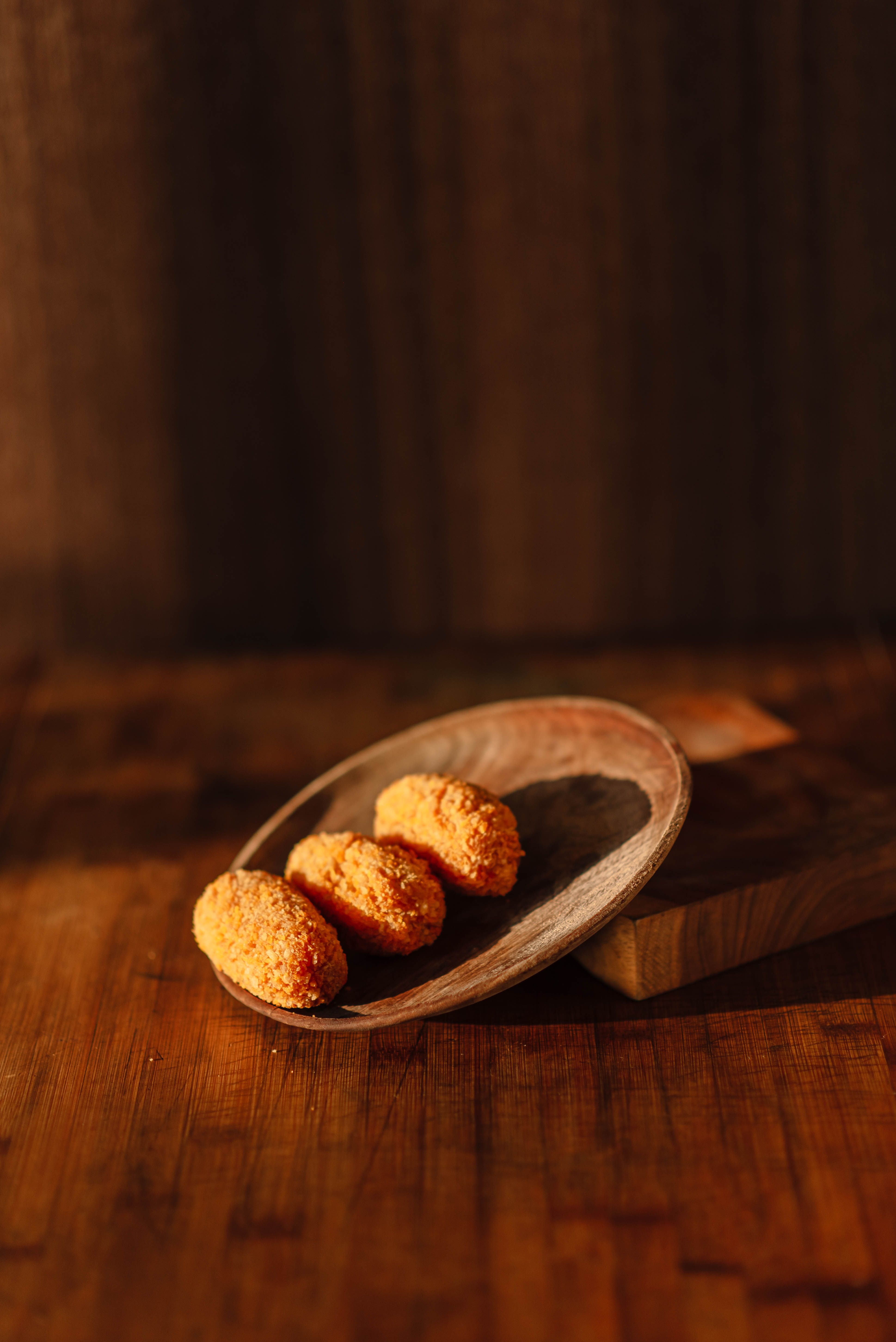 Golden cheese balls presented on a rustic wooden platter with warm lighting.