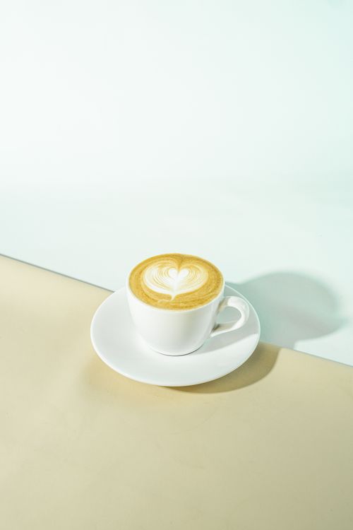 Free A cup of coffee with heart-shaped latte art on a minimalist background, perfect for cafes or coffee topics. Stock Photo