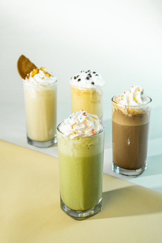 Four milkshakes in matcha, vanilla, cookie and mocha flavors topped with whipped cream