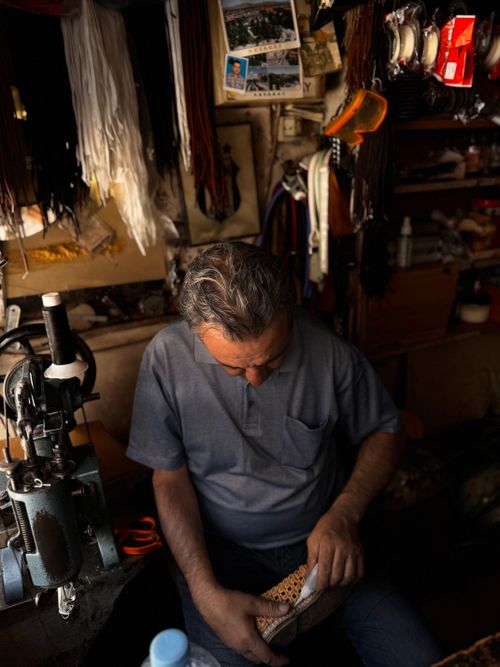 Free An artisan repairs a shoe in a cozy, traditional workshop filled with materials and tools. Stock Photo