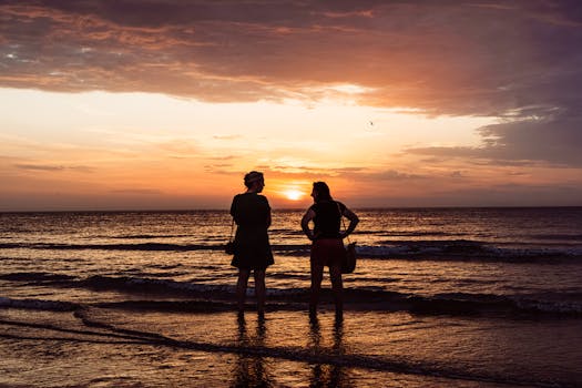 Silhouette of two people standing on Middelkerke beach at sunset, capturing a serene and vibrant evening.