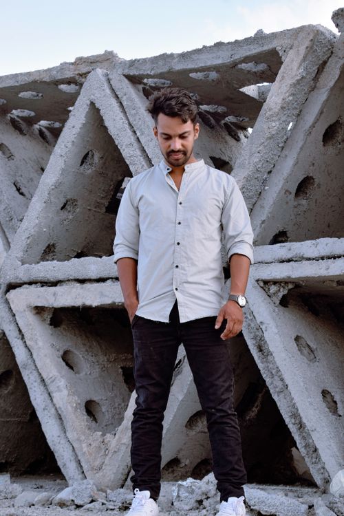 Free Young man stands confidently beside large geometric concrete shapes outdoors. Stock Photo