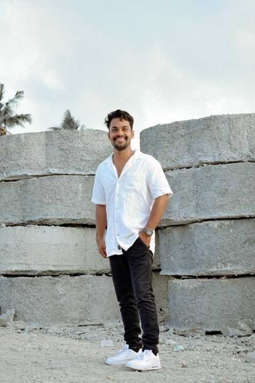 Free A stylish man in casual attire poses by large stone blocks, exuding confidence and style. Stock Photo
