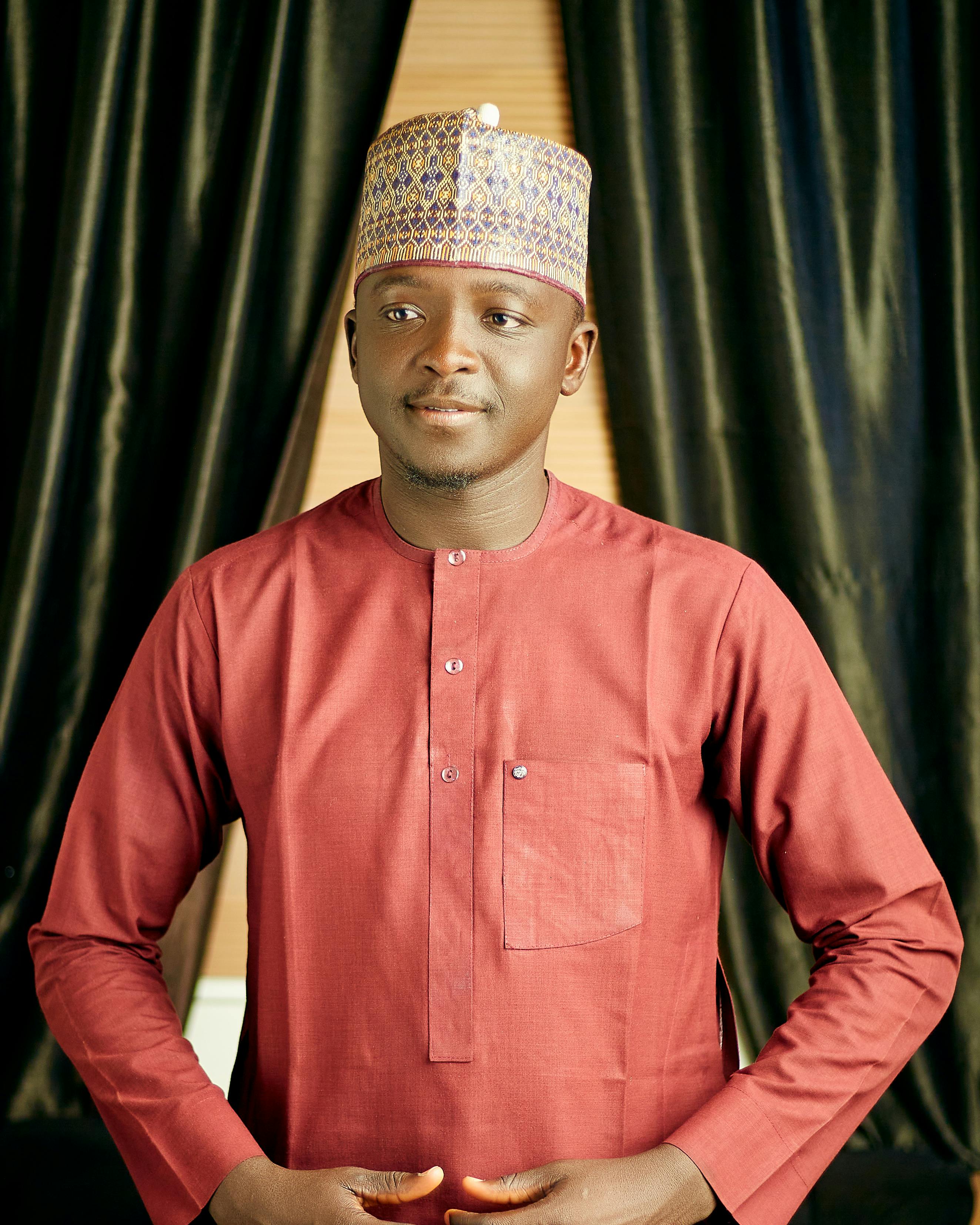 Portrait of an adult man wearing traditional attire, smiling indoors.
