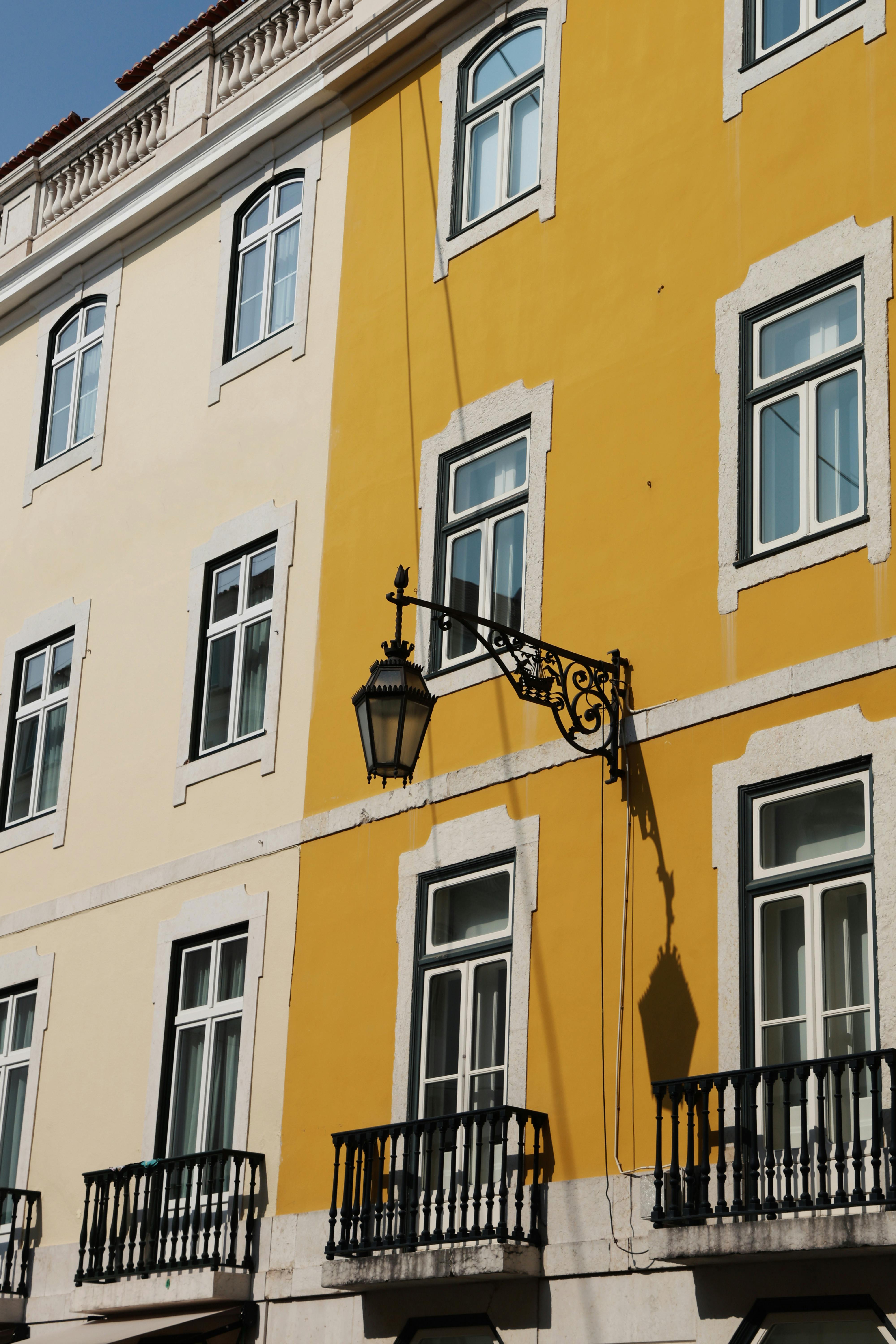 Charming European building facade featuring vibrant yellow walls and black balconies, exuding classic architectural charm.