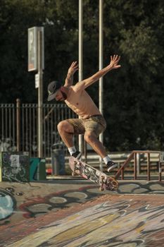 Skilled skateboarder performing a trick at an outdoor skate park on a sunny day.