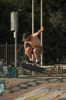 Shirtless skateboarder mid-air performing a trick at an outdoor skatepark, showcasing agility and skill.. shirtless, skateboa