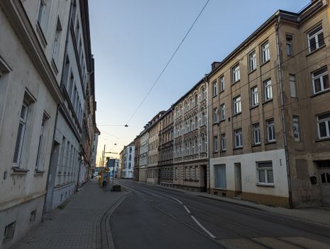 Quiet street with historic European buildings and tram tracks during dusk, creating a serene cityscape.