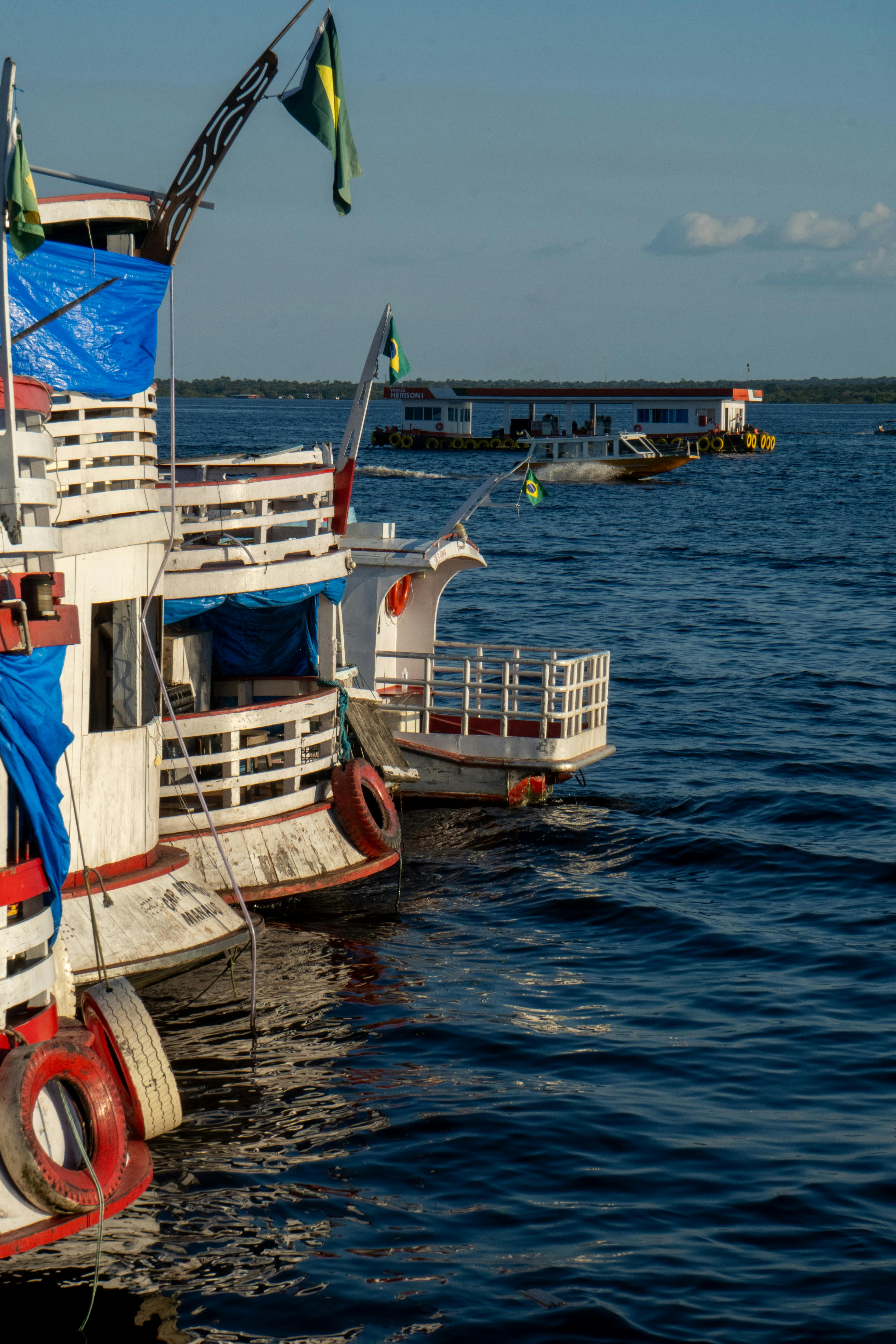 Traditional wooden boats moored on the Amazon River in Manaus during the day.