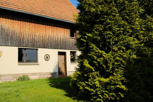 Free Cozy countryside house exterior with vibrant greenery under bright daylight. Stock Photo